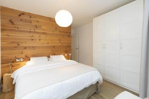a bedroom with a large white bed with a wooden wall at Acentor Alpino by BeValle in Panticosa