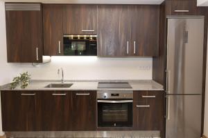 a kitchen with wooden cabinets and a stainless steel refrigerator at Sueños del Garmo by BeValle in Panticosa