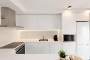 a white kitchen with a sink and a microwave at Sky Biescas I by BeValle in Biescas