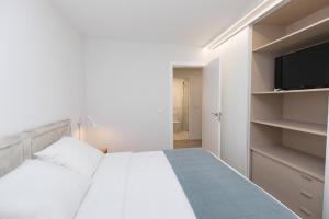 a white bedroom with a bed and a flat screen tv at Sky Biescas I by BeValle in Biescas +14 photos