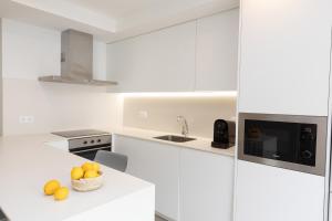 a white kitchen with a bowl of oranges on a counter at Sky Biescas I by BeValle in Biescas