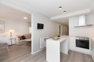 a white kitchen and living room with a couch at Sky Biescas I by BeValle in Biescas
