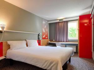 a hotel room with a large bed and a desk at ibis Abbeville in Abbeville