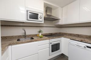 a white kitchen with a sink and a microwave at Ripereta by BeValle in Panticosa