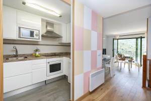 a kitchen with white cabinets and a pink and white striped wall at Ripereta by BeValle in Panticosa