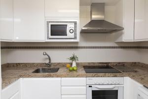 a white kitchen with a sink and a microwave at Ripereta by BeValle in Panticosa