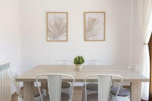a dining room table with white chairs and two pictures on the wall at Aura de Gavin by BeValle in Buesa