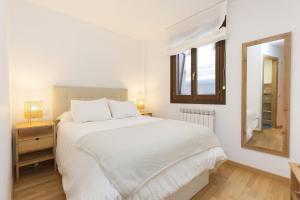 a white bedroom with a bed and a mirror at Calma by BeValle in Panticosa +17 photos