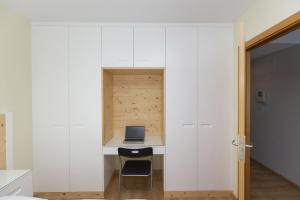 a small kitchen with white cabinets and a desk with a laptop at Casa Lite by BeValle in Escarrilla