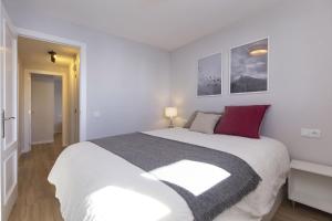 a white bedroom with a large white bed with red pillows at La Ventana de Formigal by BeValle in Formigal