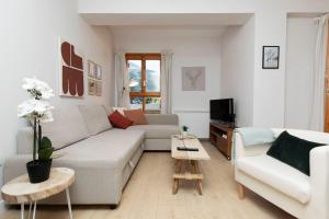 a white living room with a couch and a tv at Casa Josephine by BeValle in Panticosa