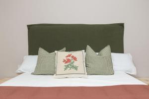 a bed with four pillows and a green headboard at Balaitus by BeValle in Escarrilla