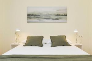 a white bed with two lamps and a painting above it at TenaNatura Ski by BeValle in Escarrilla +17 photos