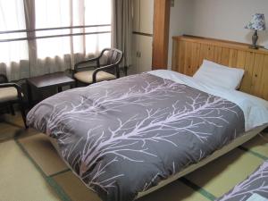 a bedroom with a bed with a gray comforter at Hotel Viva Nikko in Nikko