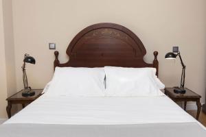 a bed with a wooden headboard and two lamps at Montibel by BeValle in Panticosa
