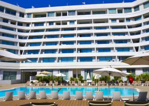 a large building with a pool and chairs and umbrellas at sea&sky luxury suite מילה דירות אירוח in Eilat +13 photos