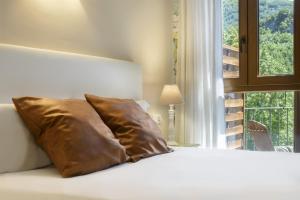 a bed with a brown pillow in a room with a window at El Rincón del Verde by BeValle in Panticosa