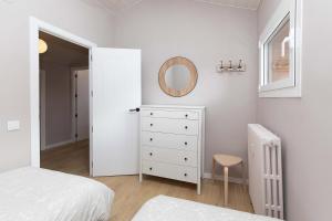 a white bedroom with a white dresser and a mirror at Ático del Prado by BeValle in Sallent de Gállego