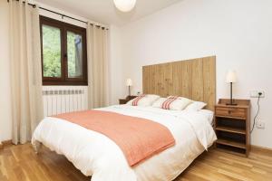a white bedroom with a large bed and a window at Casa Eguzkilore by BeValle in Escarrilla