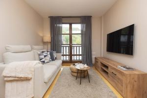 a living room with a white couch and a flat screen tv at Casa Lluna by BeValle in El Pueyo de Jaca