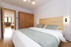 a bedroom with a large white bed with a wooden headboard at Sueños de Telera by BeValle in El Pueyo de Jaca