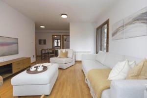 a living room with a white couch and chairs at Sueños de Telera by BeValle in El Pueyo de Jaca