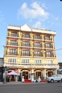 un edificio amarillo con coches estacionados frente a él en Phasouk Vien Chantra Hotel, en Vientiane