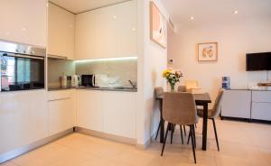 a kitchen with white cabinets and a table and chairs at West One - Luggage Facility Available in Gibraltar