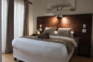 a bedroom with a large bed with a wooden headboard at Villa Mariss Guesthouse in Kraaifontein