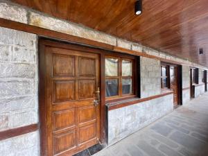 a brick building with a wooden door and windows at Kedarnath Aastha Path ME5 Building in Kedārnāth