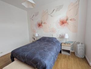 a bedroom with a bed with flowers on the wall at Appartement du parc in Ambert