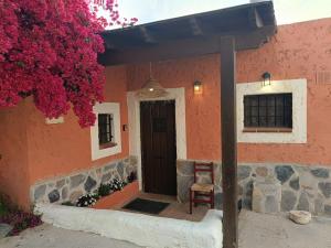 a red house with a wooden door and a chair at casita la bugamvilla in Mojácar