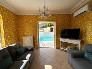 a living room with a couch and a tv at Villa Kaminia Rose private pool & Jacuzzi in Ratzaklíon