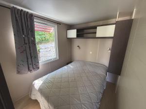 a small bedroom with a bed and a window at CAMPING PANORAMIQUE du VERDON in Castellane