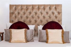 two pillows on a bed with a padded headboard at Oue Werf Country House in Oudtshoorn