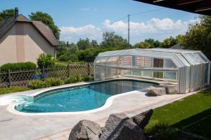 a swimming pool with a greenhouse in a yard at Dôme du levant SPA Cinéma Piscine et Climatisation in Holving