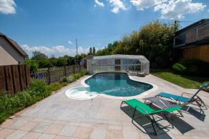 a swimming pool with two chairs and a glass house at Dôme du levant SPA Cinéma Piscine et Climatisation in Holving