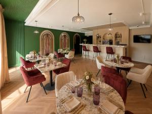 a restaurant with tables and chairs and a green wall at Hôtel Le Clos des Arts in Gevrey-Chambertin