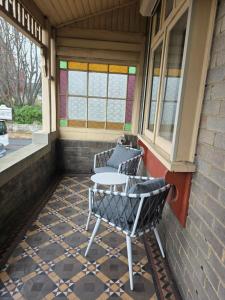 a patio with two chairs and a table on a porch at The Red Manor on Mort in Lithgow