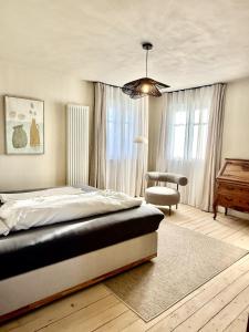 a bedroom with a bed and a chair and a table at Villa El Jardin Bodensee in Lochau