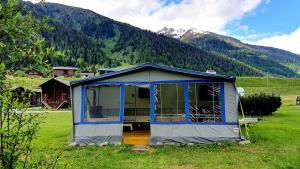 a small tent in a field with a mountain at Brigga Camping Mietwohnwagen in Ritzingen