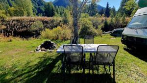 a table and chairs in a field next to a van at Brigga Camping Mietwohnwagen in Ritzingen +14 photos