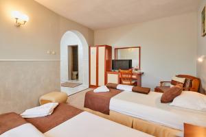 a hotel room with two beds and a desk at Peneka Hotel in Pomorie