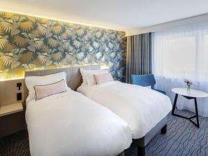 a hotel room with two beds and a table at Grand Hotel Bregenz - MGallery Collection in Bregenz