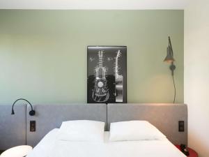a bedroom with a bed with a picture on the wall at ibis Reims Tinqueux in Reims
