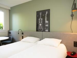 a bedroom with two beds and a guitar on the wall at ibis Reims Tinqueux in Reims
