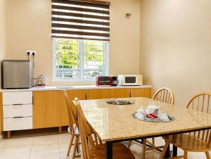a kitchen with a table with chairs and a microwave at Family Retreat w Kid Pool, BBQ Games Sleeps 10pax Melaka in Kampong Beringin