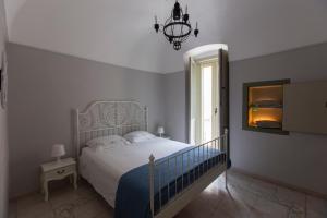 a bedroom with a bed and a chandelier and a window at Nel Blu Dipinto di Blu - Casa Anemone in Polignano a Mare