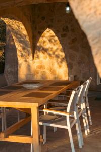 a wooden table and chairs in front of a stone wall at IoMi Terra & Mare in Eleonas +50 photos
