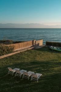 four chairs sitting in the grass near the water at IoMi Terra & Mare in Eleonas